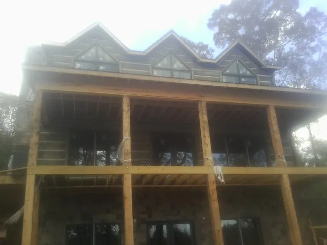 Dormers and porch framing on a large log home under construction — Roof Coating work by our crew in California